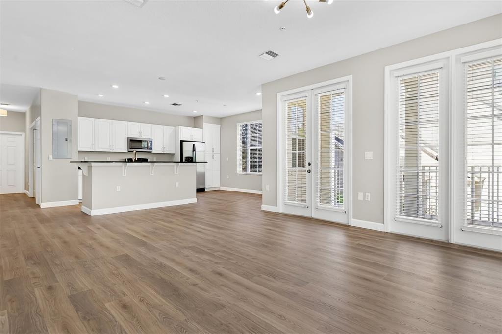 An open-concept kitchen and living area with white cabinets, dark countertops, and wood-look flooring — 4392 WARDELL PLACE UNIT 201, ORLANDO, FL