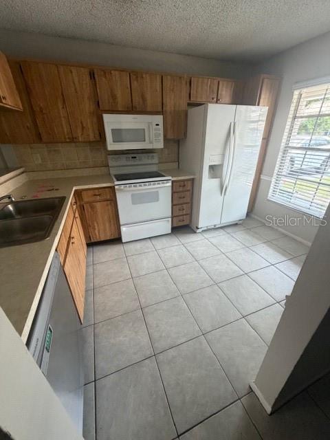 A kitchen features wood cabinets, white appliances, and light-colored tile flooring — 300 KENT PLACE, SAFETY HARBOR, FL