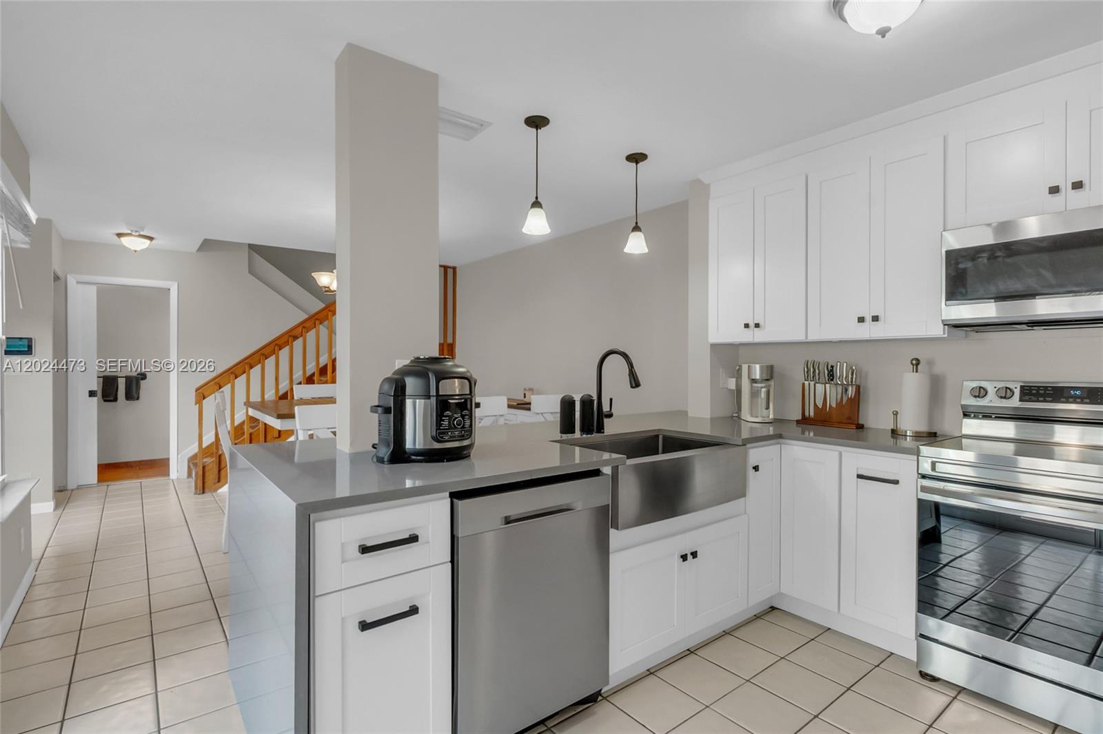 A kitchen features white cabinets, stainless steel appliances, a farmhouse sink, and gray countertops — 11022 Chandler Dr, Cooper City FL 33026, COOPER CITY, FL