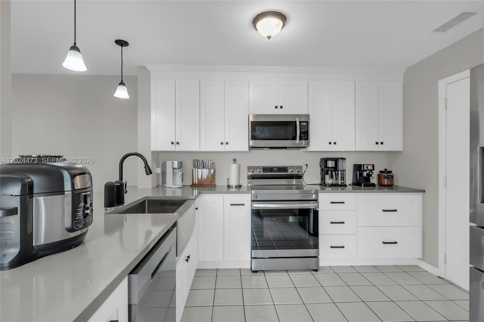 A kitchen features white cabinets, stainless steel appliances, gray countertops, and light-colored floor tiles — 11022 Chandler Dr, Cooper City FL 33026, COOPER CITY, FL