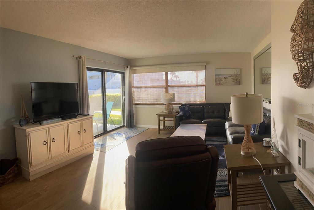 A living room features a television console, a sectional sofa, and sliding glass patio doors — 1571 S ATLANTIC AVENUE UNIT 106, NEW SMYRNA BEACH, FL