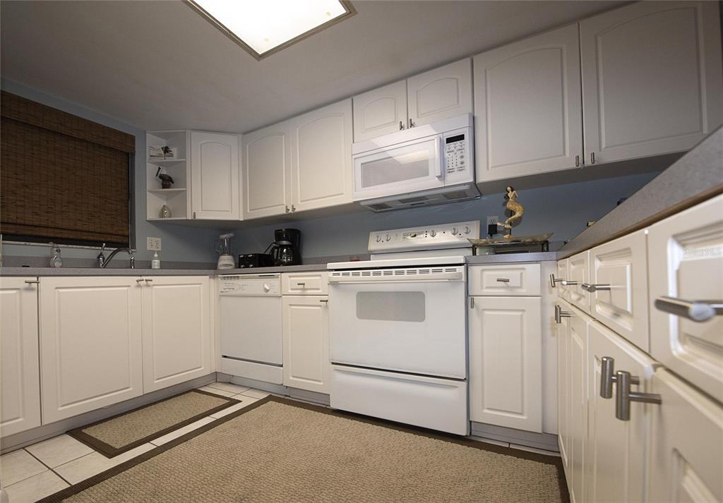 A kitchen features white cabinets, white appliances, a gray countertop, and a light-colored tile floor — 1571 S ATLANTIC AVENUE UNIT 106, NEW SMYRNA BEACH, FL
