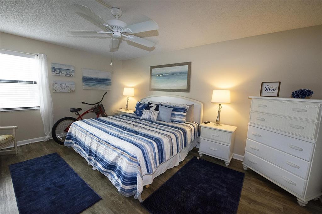 A bedroom features a bed with blue striped bedding, two nightstands, and a white dresser — 1571 S ATLANTIC AVENUE UNIT 106, NEW SMYRNA BEACH, FL