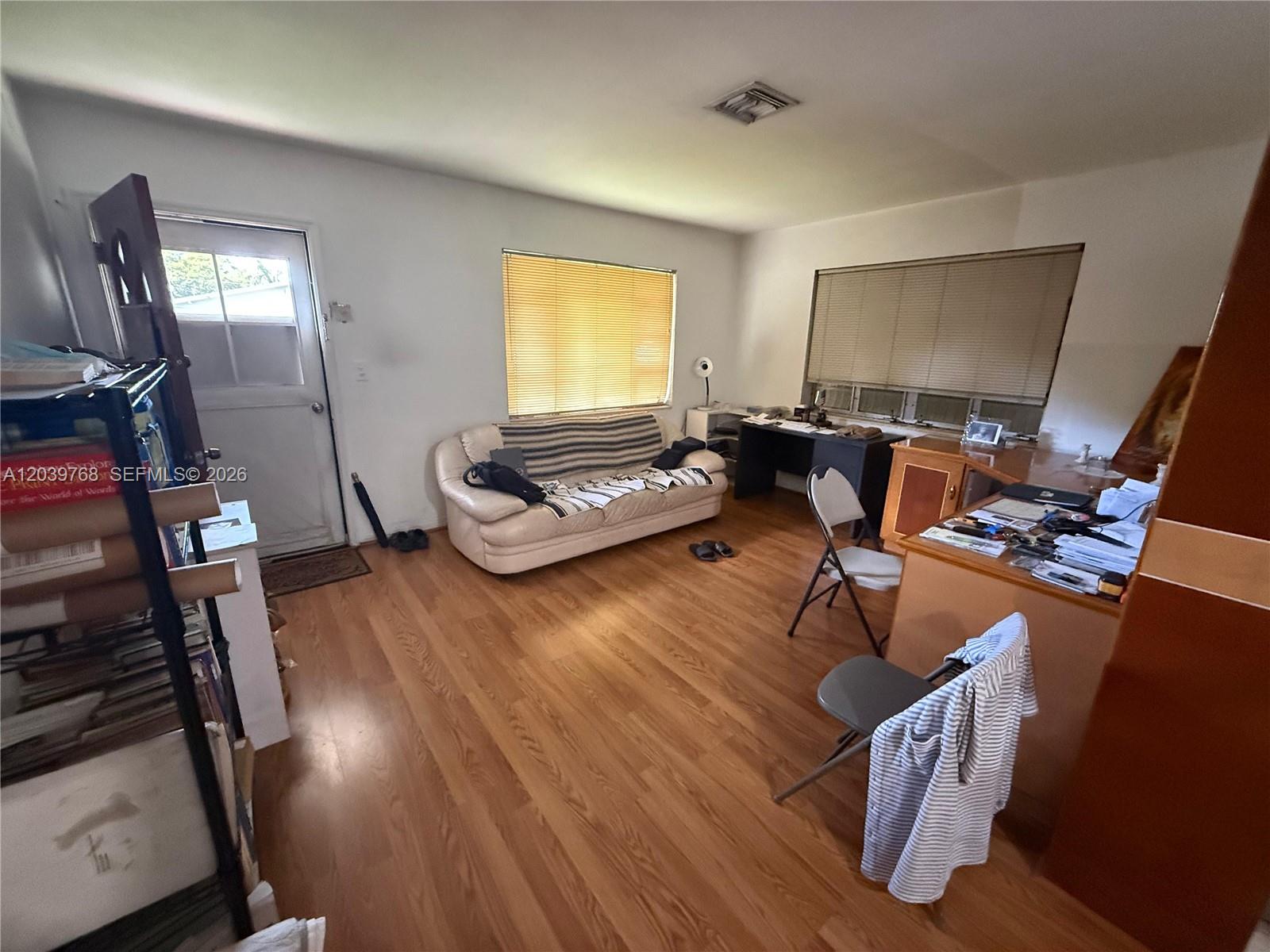 A room with wood flooring, a white sofa, a desk, and a door to outside — 2447 Arthur St, Hollywood FL 33020, HOLLYWOOD, FL