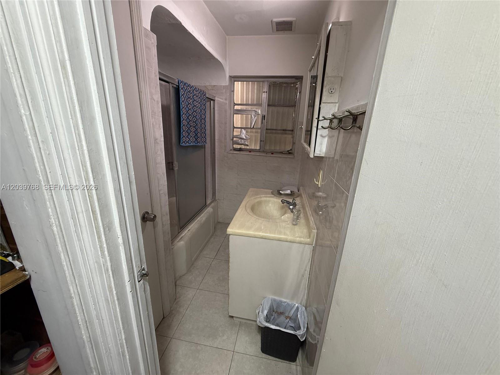 A bathroom features a vanity with a sink, a shower-tub combination, and a window — 2447 Arthur St, Hollywood FL 33020, HOLLYWOOD, FL