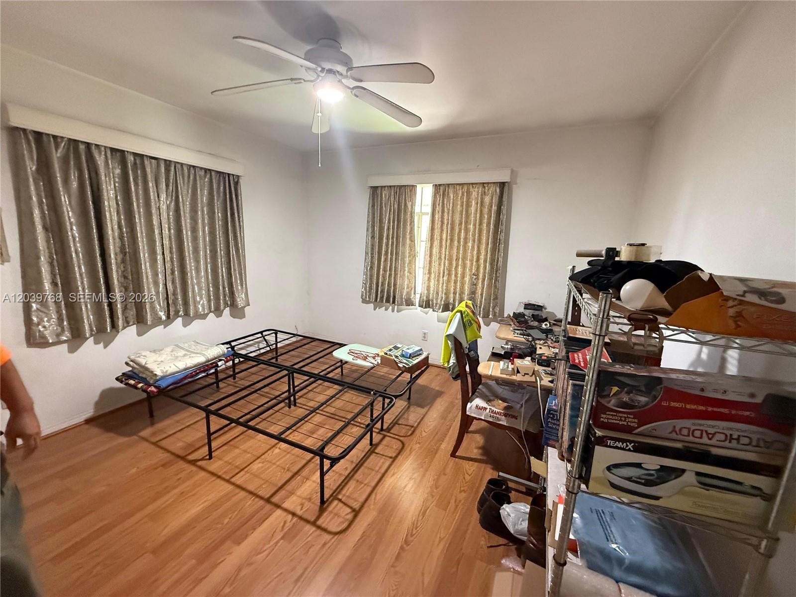 A bedroom with wood-look flooring, two metal bed frames, and a metal storage rack — 2447 Arthur St, Hollywood FL 33020, HOLLYWOOD, FL