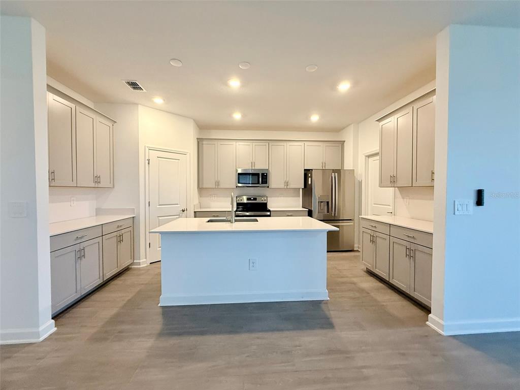 A kitchen with light gray cabinets, white countertops, a central island, and stainless steel appliances — 2410 RELAXING LANE, KISSIMMEE, FL
