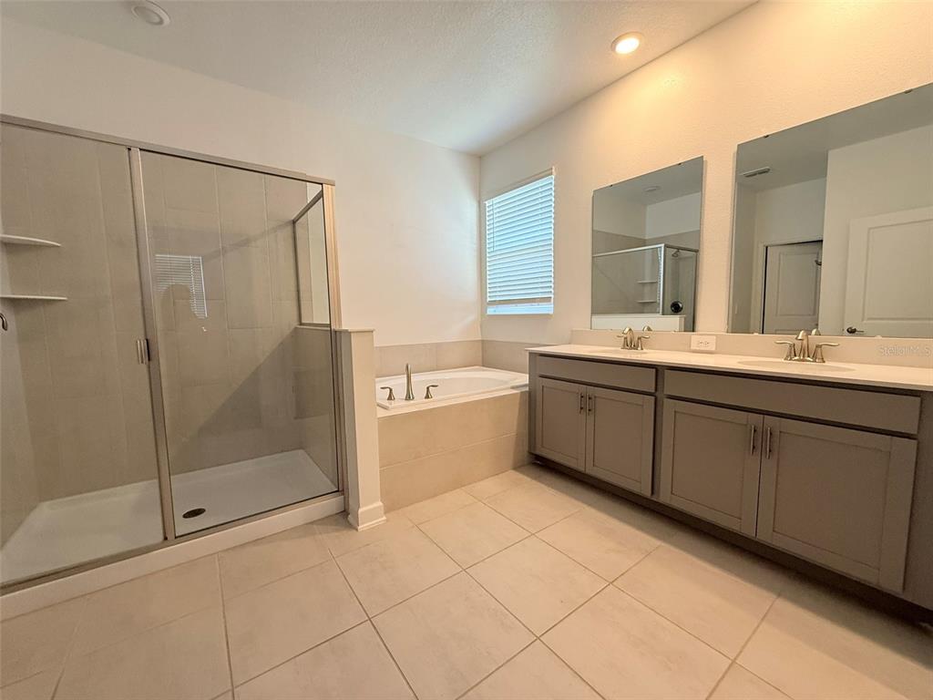 A bathroom features a glass-enclosed shower, a soaking tub, and a double-sink vanity — 2410 RELAXING LANE, KISSIMMEE, FL