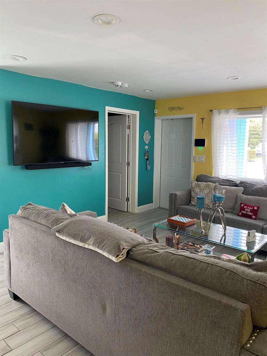 A living room features a teal accent wall, a grey sofa, and a glass coffee table — 416 N D Street # 2, FL 33460, FL