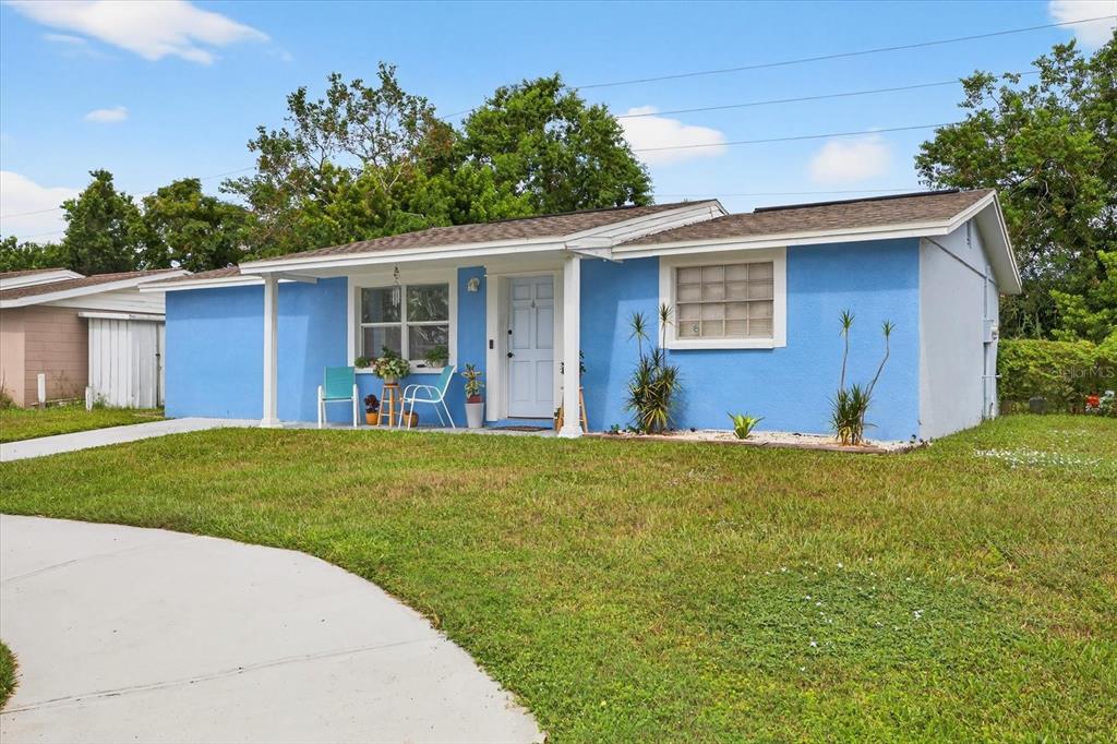 A single-story blue house with a white front door and a concrete walkway — 7811 FOX HOLLOW DRIVE, PORT RICHEY, FL