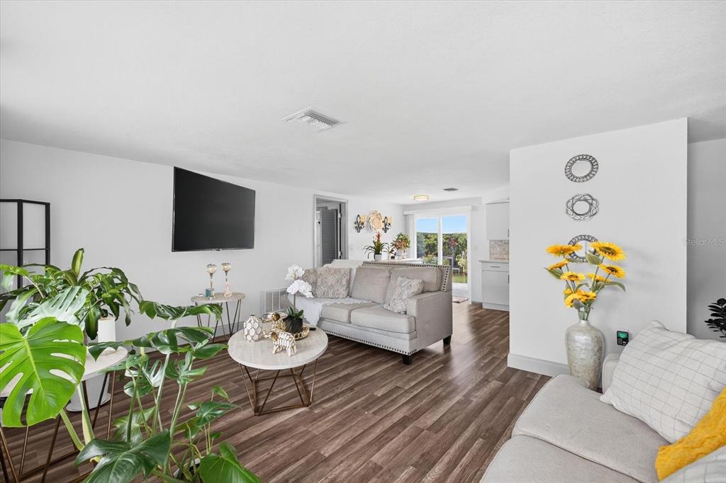 A living room features light gray sofas, a round coffee table, and wood-look flooring — 7811 FOX HOLLOW DRIVE, PORT RICHEY, FL