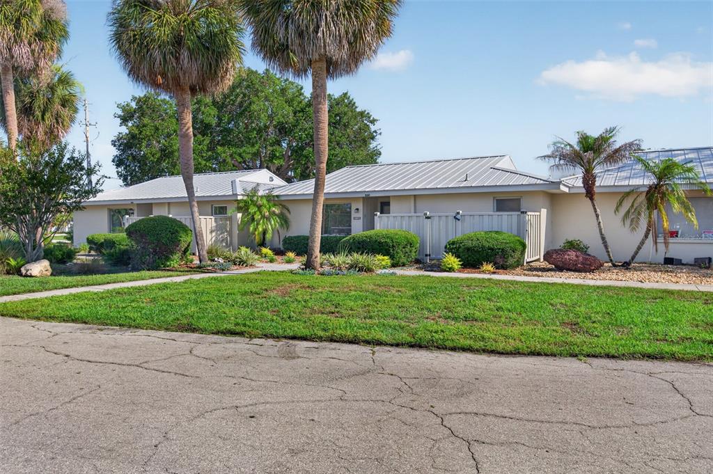 A single-story building with a metal roof, palm trees, and a landscaped front yard — 11643 W KING FISHER COURT UNIT 200, CRYSTAL RIVER, FL