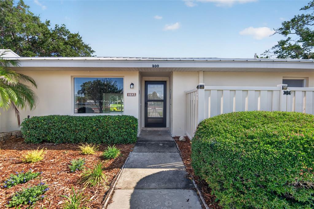 A concrete walkway leads to the front entrance of a single-story home with landscaping — 11643 W KING FISHER COURT UNIT 200, CRYSTAL RIVER, FL