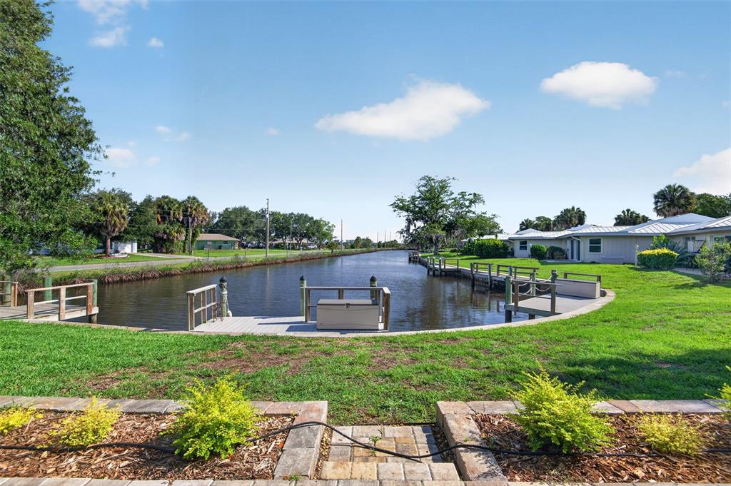 A canal view from a grassy backyard featuring a wooden dock and residential buildings — 11643 W KING FISHER COURT UNIT 200, CRYSTAL RIVER, FL