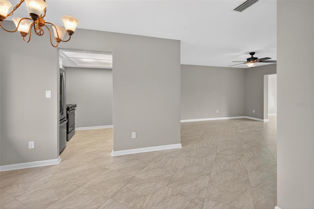 An open-concept room features light gray walls, large beige floor tiles, and a ceiling fan — 11643 W KING FISHER COURT UNIT 200, CRYSTAL RIVER, FL