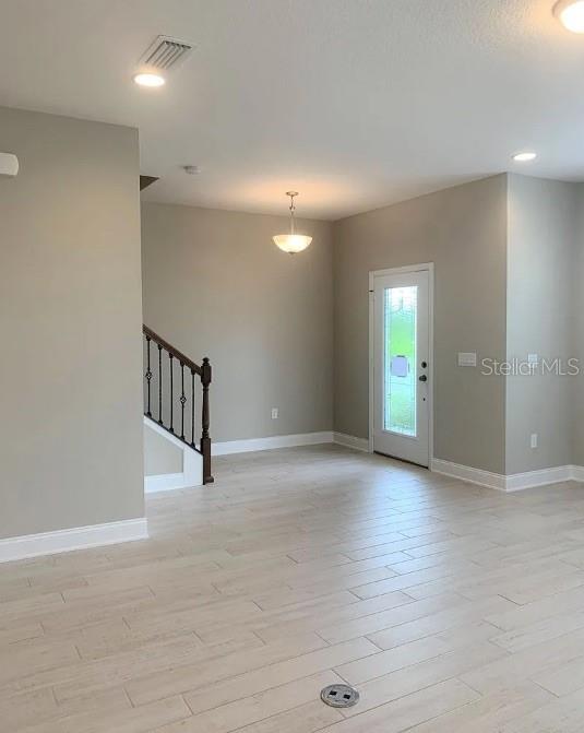 An interior view shows a foyer with light wood-look tile flooring, a staircase, and a door — 13075 SPRING GROVE WAY, WINTER GARDEN, FL