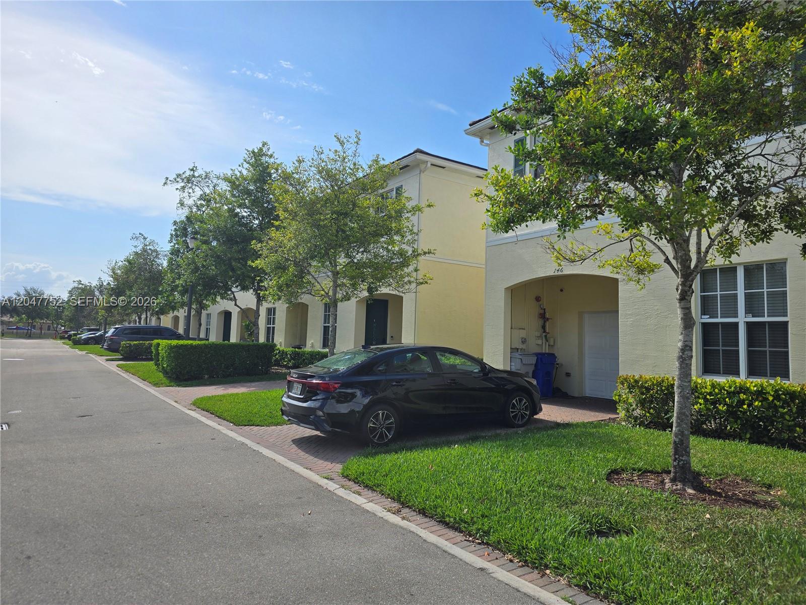 A black sedan is parked in the driveway of a yellow two-story townhouse — 146 SW 7th Ct, Pompano Beach FL 33060, POMPANO BEACH, FL