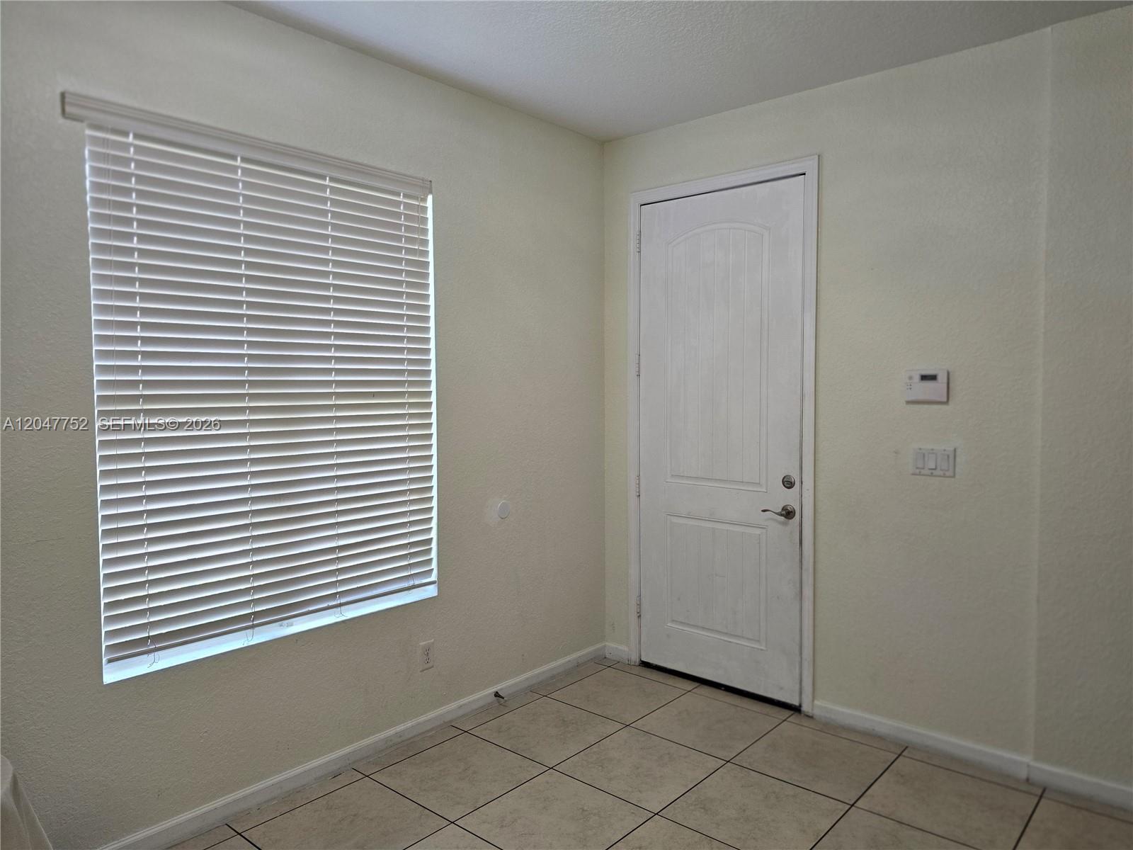 A room with tiled floors, a window with white blinds, and a white door — 146 SW 7th Ct, Pompano Beach FL 33060, POMPANO BEACH, FL