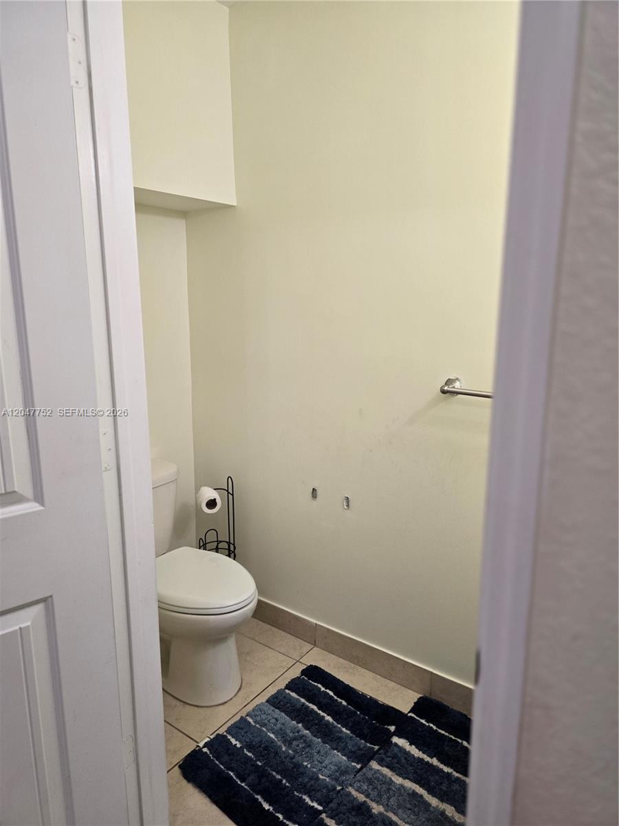 A small bathroom features a white toilet, a towel bar, and a blue rug — 146 SW 7th Ct, Pompano Beach FL 33060, POMPANO BEACH, FL