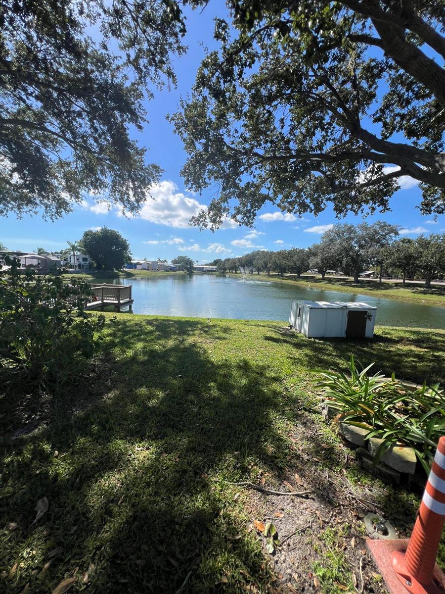 A grassy yard overlooks a pond with a wooden dock and a small white structure — 7950 Florida 78, Okeechobee FL 34974, OKEECHOBEE, FL