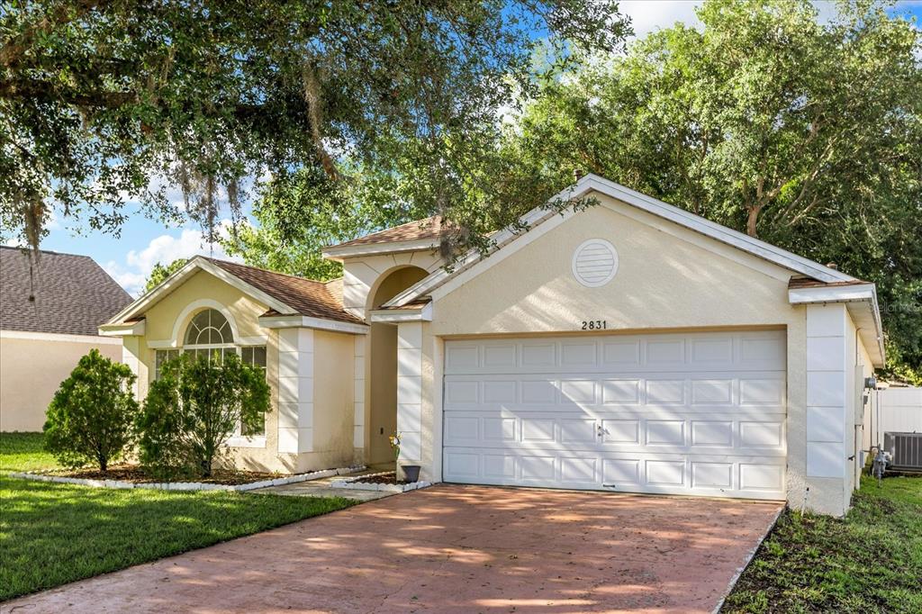 A single-story house with a two-car garage, stucco exterior, and a front-facing arched window — 2831 WILSHIRE ROAD, CLERMONT, FL