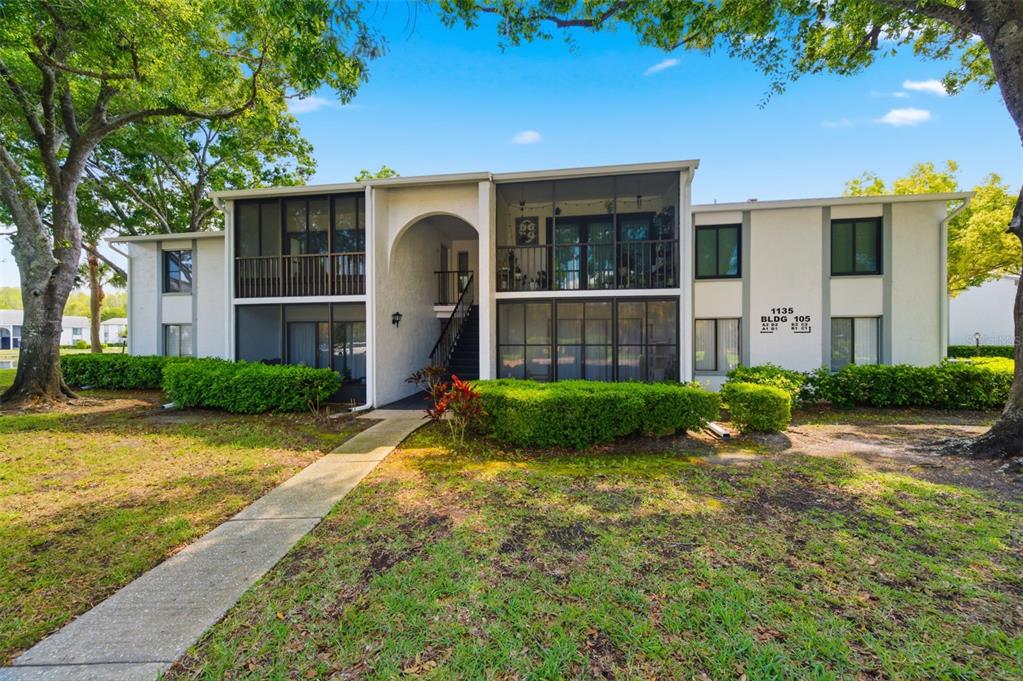 A two-story apartment building with screened balconies and a central arched entryway — 1135 PINE RIDGE CIRCLE W UNIT A2, TARPON SPRINGS, FL