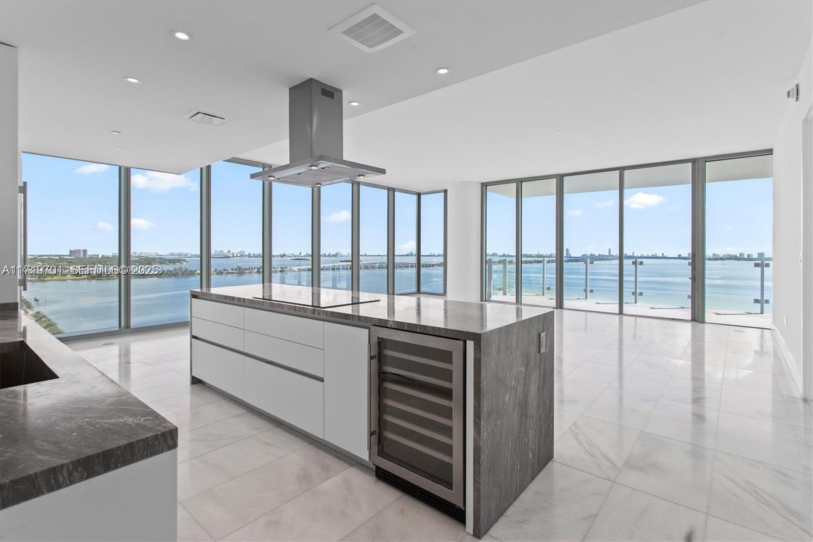 A modern kitchen features a stone island with a wine cooler and floor-to-ceiling windows — 700 NE 26th Ter # 2001, Miami FL 33137, MIAMI, FL