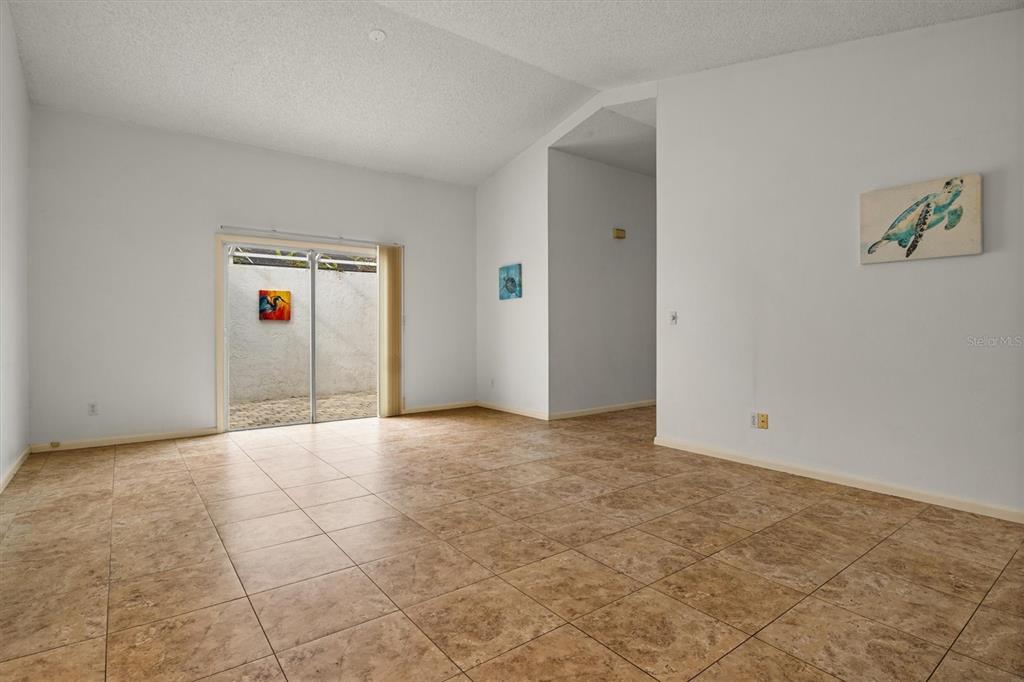 An empty room with beige tile flooring, white walls, and a sliding glass door — 381 SAN JOSE DRIVE, WINTER HAVEN, FL