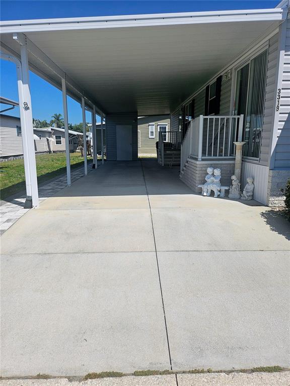 A concrete driveway leads to a covered carport beside a manufactured home with exterior steps — 3319 OVERCUP OAK TERRACE, SARASOTA, FL