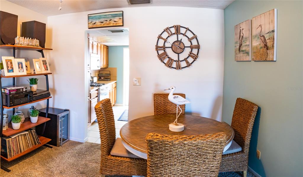A dining area features a round wooden table, wicker chairs, and a large wall clock — 3018 59TH STREET S UNIT 309, GULFPORT, FL