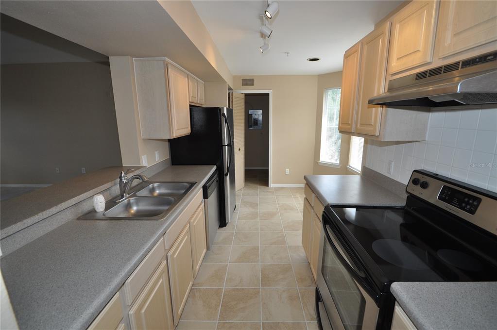 A galley-style kitchen features light wood cabinets, gray countertops, and stainless steel appliances — 408 SUMMIT RIDGE PLACE UNIT 316, LONGWOOD, FL