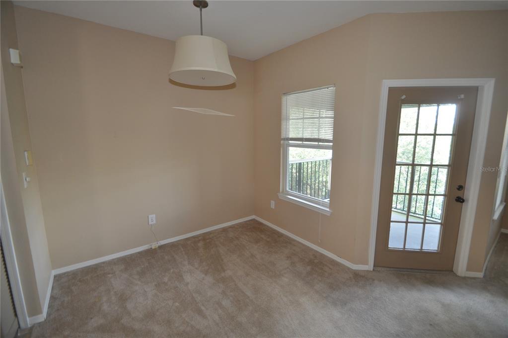 An empty room with beige walls, carpeted flooring, a pendant light, a window, and a door — 408 SUMMIT RIDGE PLACE UNIT 316, LONGWOOD, FL
