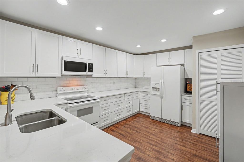 A kitchen with white cabinets, white countertops, stainless steel sink, and wood-look flooring — 13507 PALMWOOD LANE UNIT 13507, TAMPA, FL
