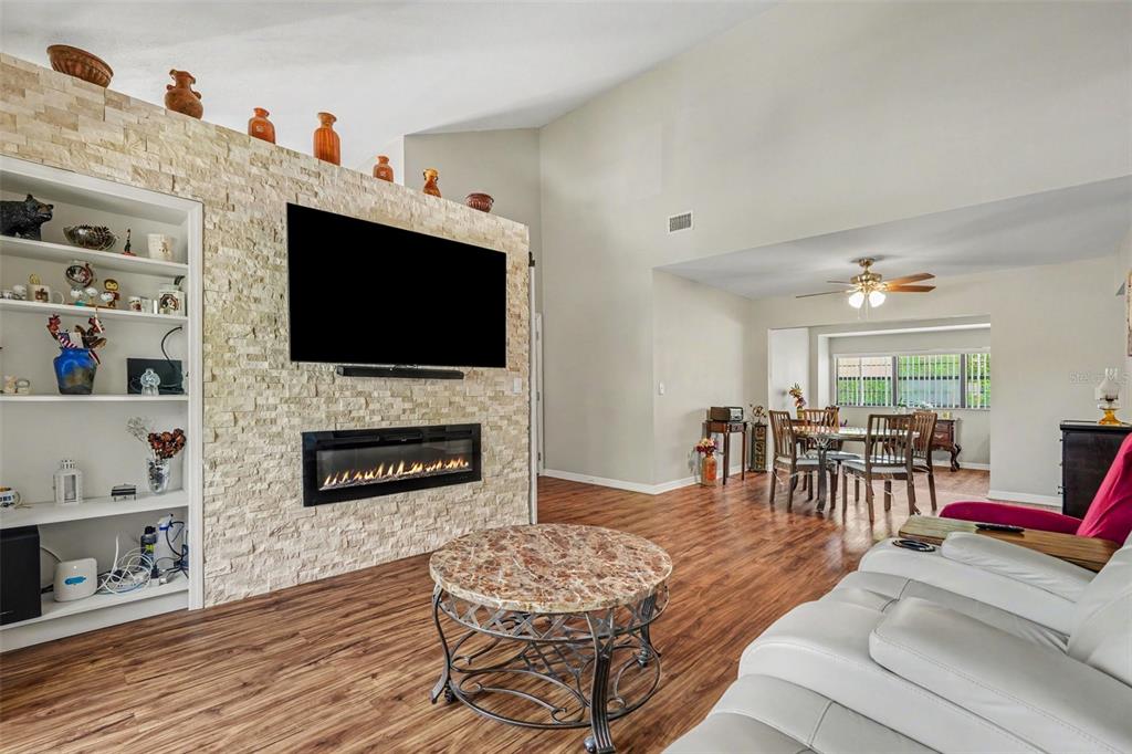 A living room features a stone fireplace wall with a mounted television and built-in shelving — 13507 PALMWOOD LANE UNIT 13507, TAMPA, FL