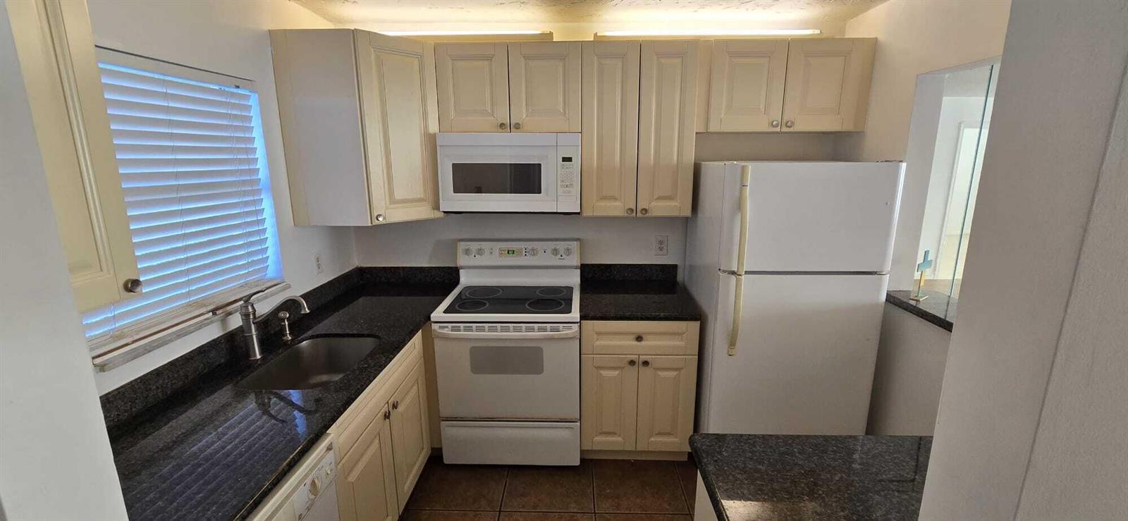 A kitchen features cream cabinets, black granite countertops, a white stove, and a white refrigerator — 9949 Sandalfoot Boulevard # 531, Boca Raton FL 33428, BOCA RATON, FL