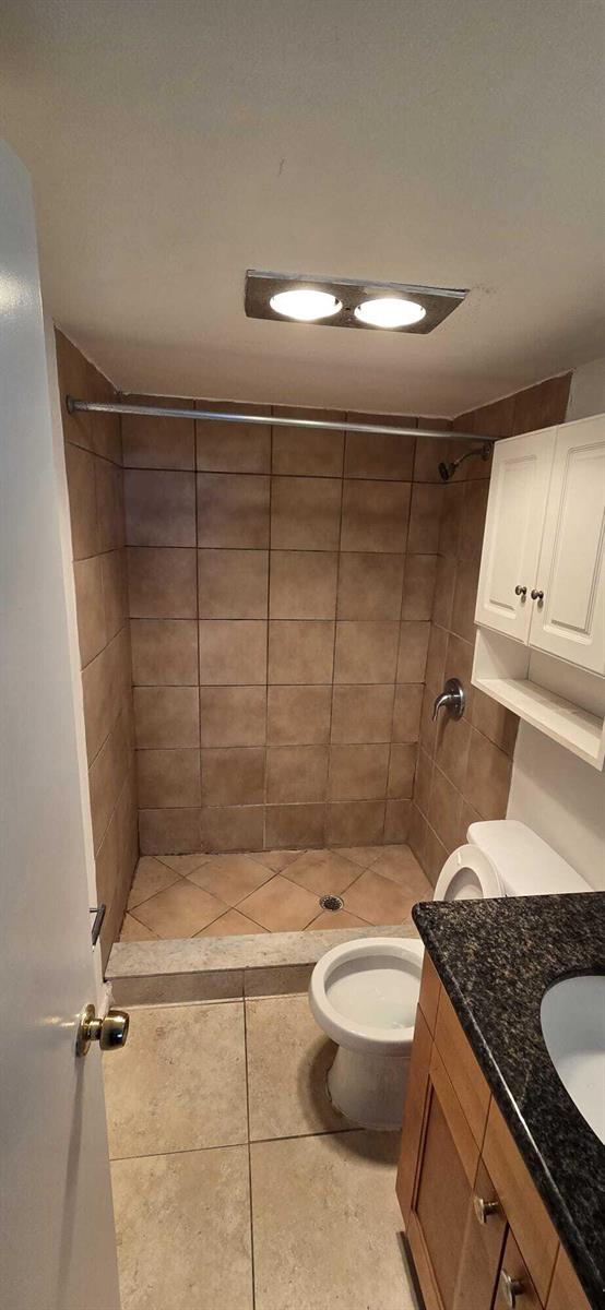 A bathroom features a tiled walk-in shower, a toilet, and a vanity with a dark countertop — 9949 Sandalfoot Boulevard # 531, Boca Raton FL 33428, BOCA RATON, FL