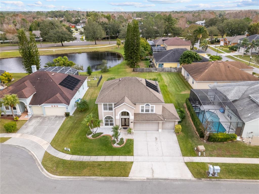 An aerial view shows a suburban house with a driveway, pool enclosure, and solar panels — 617 LAKESCAPE COURT, ORLANDO, FL