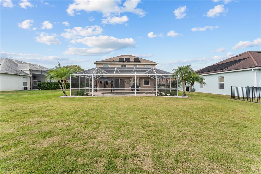 A two-story house with a screened-in pool and patio sits in a large backyard — 617 LAKESCAPE COURT, ORLANDO, FL