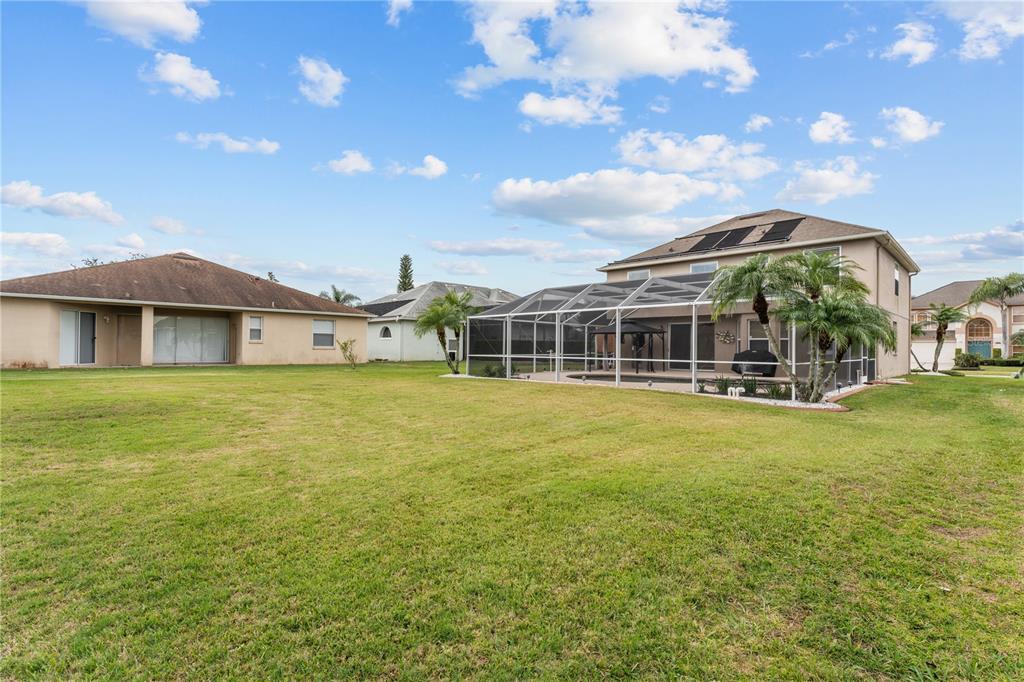 A two-story house with a screened-in pool enclosure sits on a large grassy lot — 617 LAKESCAPE COURT, ORLANDO, FL