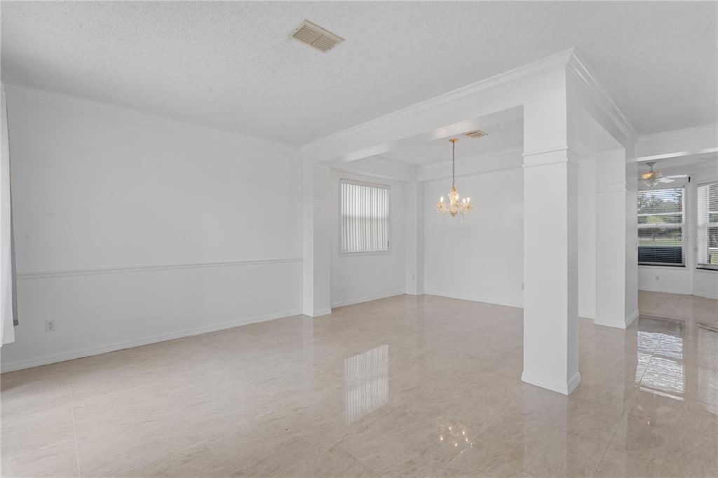 An open-concept dining area features white walls, tile flooring, and a crystal chandelier — 617 LAKESCAPE COURT, ORLANDO, FL