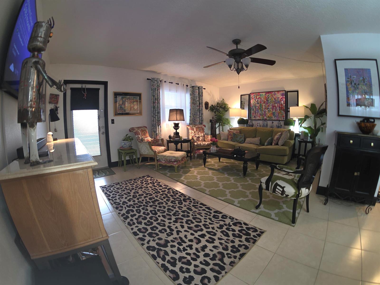 A living room features a leopard print rug, green area rug, sofa, and eclectic decor — 491 Brittany K, Delray Beach FL 33446, DELRAY BEACH, FL
