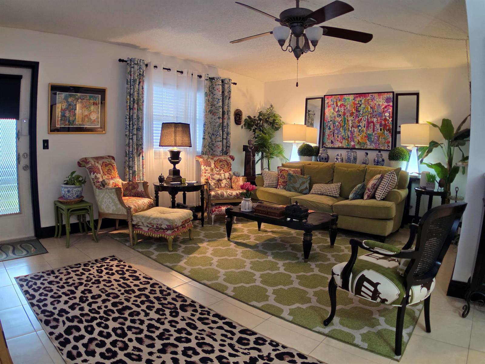 A living room features a green sofa, patterned armchairs, a coffee table, and area rugs — 491 Brittany K, Delray Beach FL 33446, DELRAY BEACH, FL