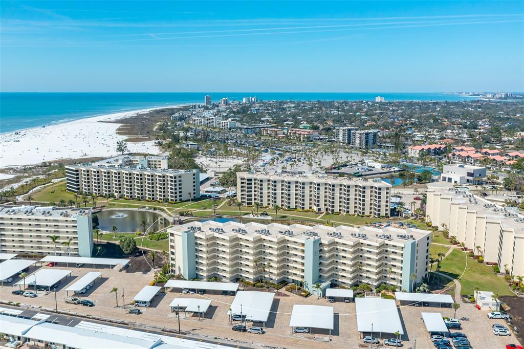 An aerial view of a multi-story apartment complex near a beach and ocean — 5780 MIDNIGHT PASS ROAD UNIT 210, SARASOTA, FL