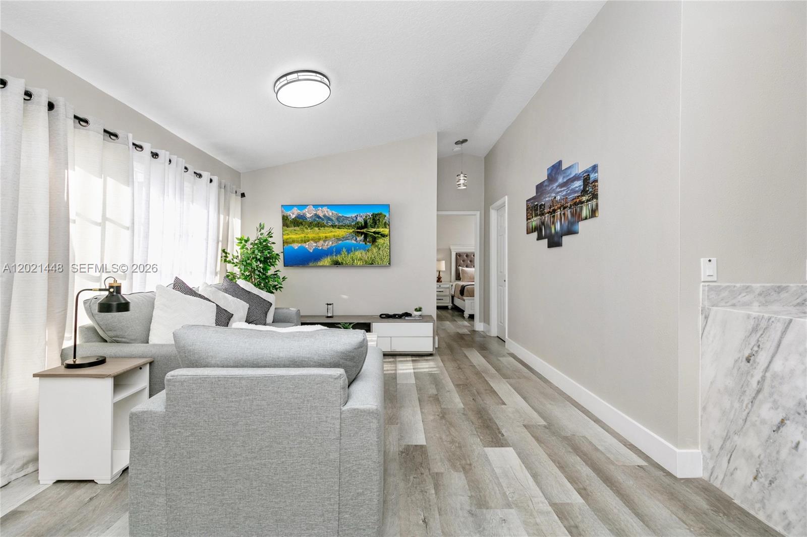 A living room features gray flooring, a wall-mounted television, and a view into a bedroom — 5608 Mandarin, Davenport FL 33986, DAVENPORT, FL