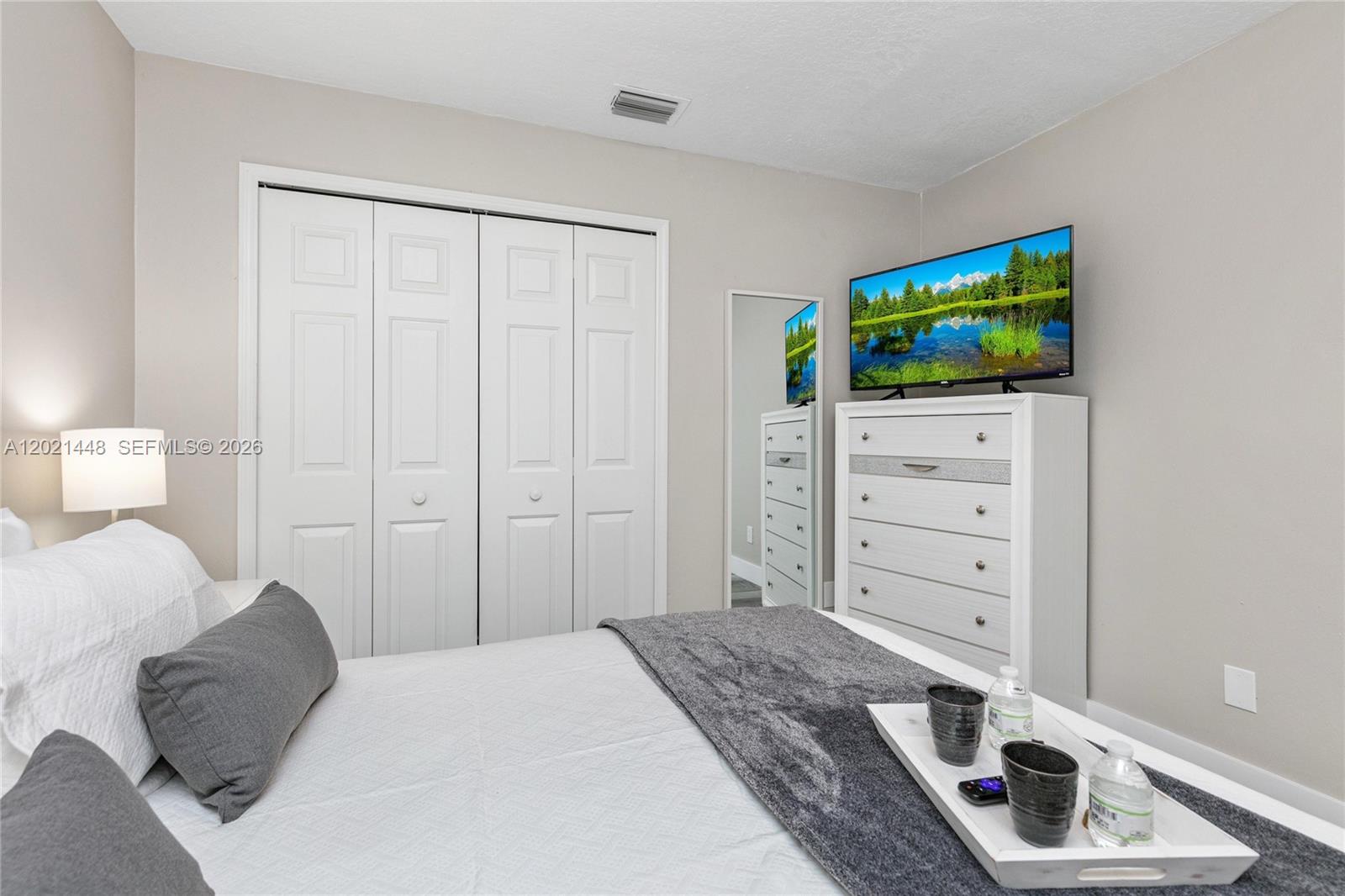 A bedroom features a bed with a gray runner, a white dresser, and closet doors — 5608 Mandarin, Davenport FL 33986, DAVENPORT, FL
