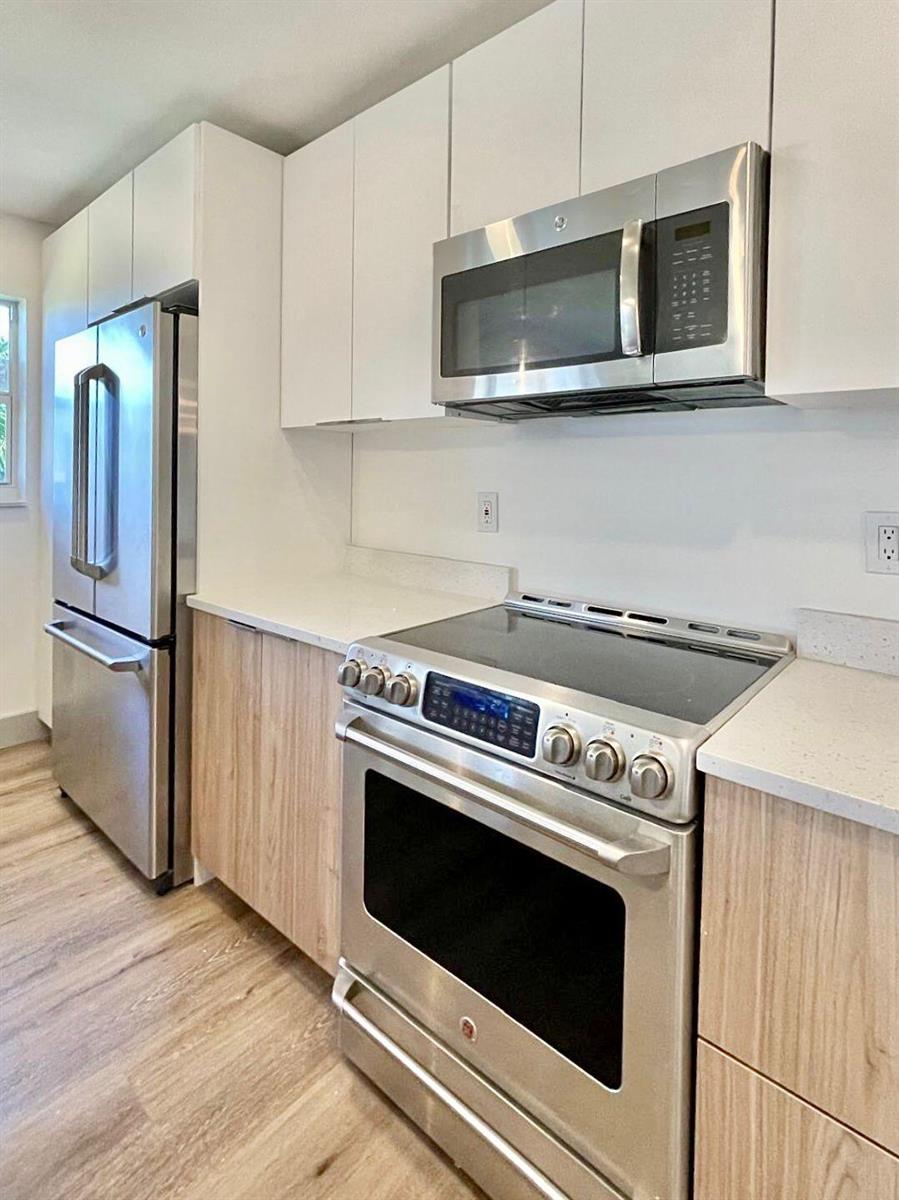 A modern kitchen features stainless steel appliances, light wood cabinets, and white countertops — 892 High Point Boulevard N # C, Delray Beach FL 33445, DELRAY BEACH, FL