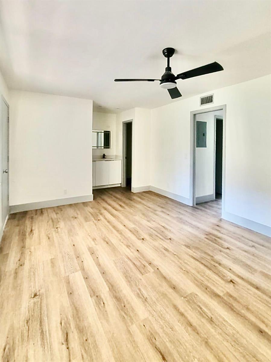 A bedroom with light wood-look flooring, white walls, and a black ceiling fan — 892 High Point Boulevard N # C, Delray Beach FL 33445, DELRAY BEACH, FL