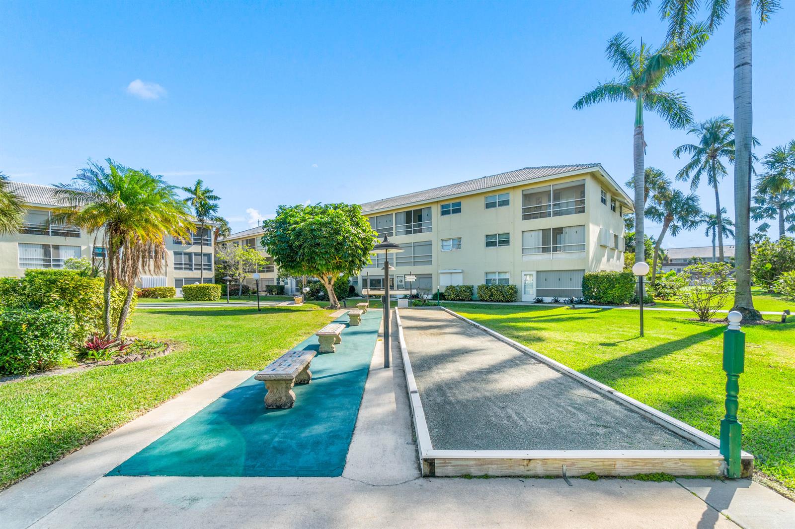 A shuffleboard court sits on a grassy lawn in front of a multi-story apartment building — 1951 NE 39th Street # 131, Lighthouse Point FL 33064, LIGHTHOUSE POINT, FL