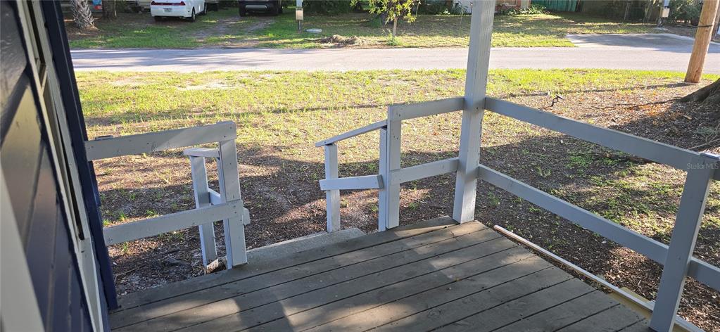 A wooden porch features a white railing and a small set of stairs leading outside — 318 CHESNEY BLVD, FROSTPROOF, FL