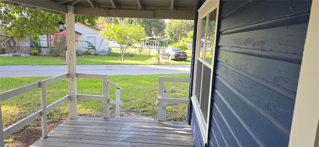 A wooden porch with white railings overlooks a grassy yard and a residential street — 318 CHESNEY BLVD, FROSTPROOF, FL